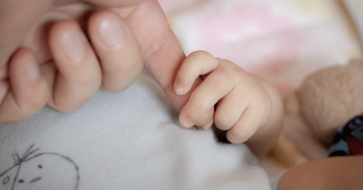 Mano adulta tomando la mano de un bebe