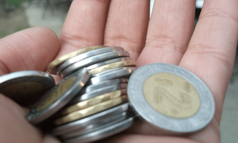 Mano sosteniendo monedas de economía mexicana